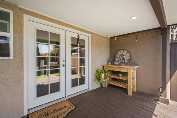 Covered outdoor area with French doors and a wooden table with plants and decor.
