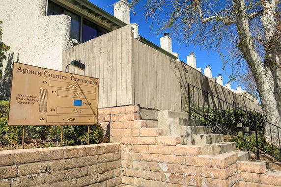Front view of a row of townhomes with a wooden fence and multiple chimneys.