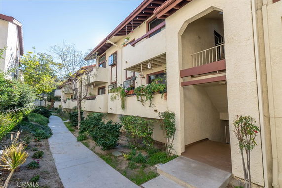 Exterior view of a multi-story residential building with balconies and a pathway.