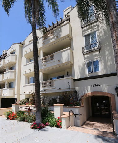 Front view of a multi-story residential building with balconies and an entrance.