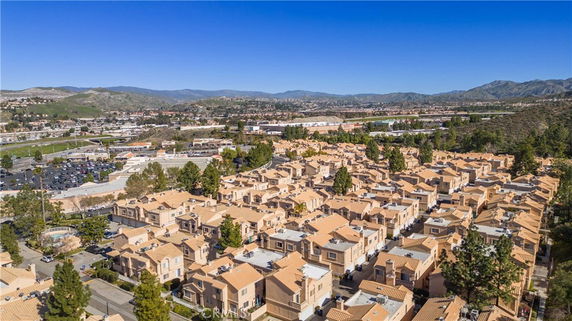 Aerial view of a residential area with numerous houses featuring terracotta roofs set in a hilly landscape.