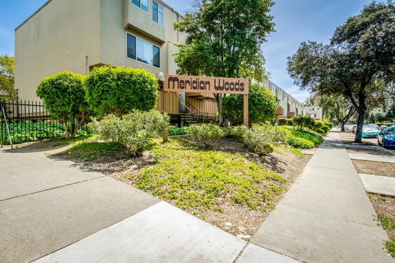 Front view of a multi-story residential building with a sign reading 'Meridian Woods'.