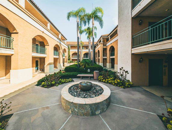 Courtyard area of a multi-level building with arches and balconies.