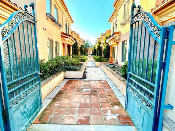 Front view of two-story residential buildings with decorative blue gates and manicured bushes.