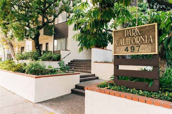 Front view of a multi-story building with stairs and a wooden sign displaying 'Park California 497'.