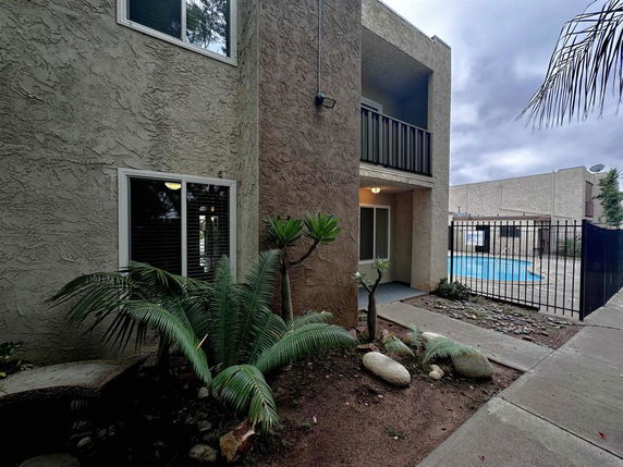 View of a building with an outdoor swimming pool enclosed by a fence.