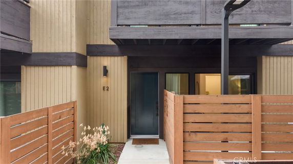 Front view of a house with wooden paneling and a small courtyard.