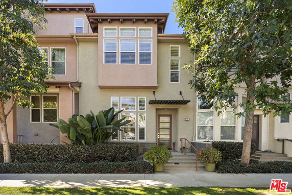 Front view of a multi-story townhouse with large windows and a small staircase leading to the entrance.