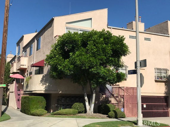 Front view of a multi-story building with pink exterior and landscaping.