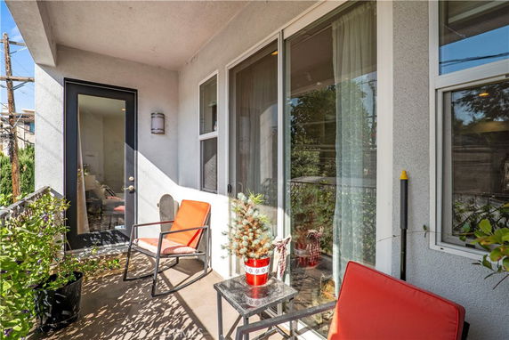 Outdoor patio area with chairs and small table, adjacent to glass door and window.