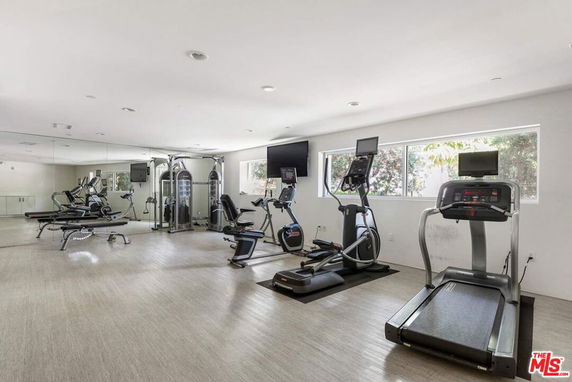Indoor gym area with exercise equipment including treadmills, bikes, and weight machines.