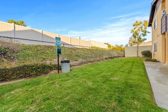 Side view of a building with adjacent grassy area and fence.