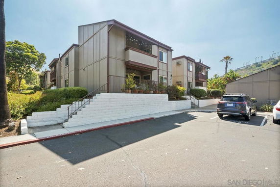 Front view of a multi-story residential building with staircase leading to entrance.