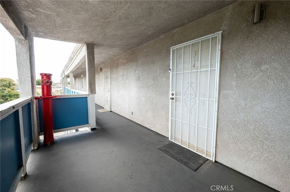 Exterior view of an apartment entrance with a security door and balcony railing.