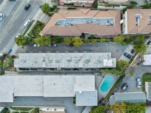 Aerial view of buildings and a swimming pool with adjacent parking space.