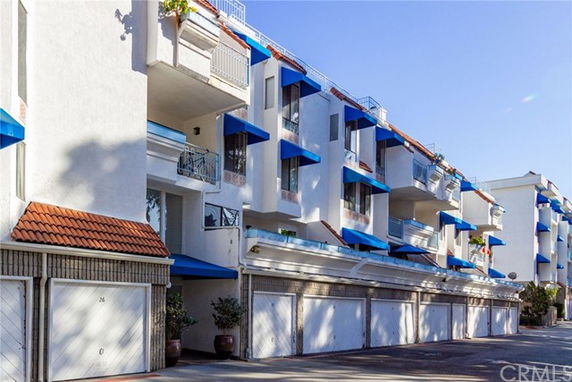 Front view of a multi-story building with blue awnings and garages on the ground floor.