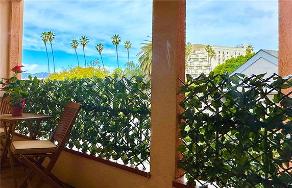 View of surrounding areas with palm trees and distant buildings from a balcony.