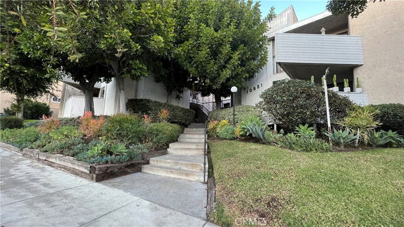 Front view of a multi-story building with balconies and stairway entrance.