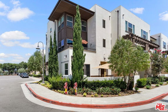 Front view of a modern multi-story building with large windows and a terrace.