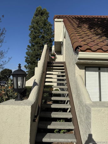 Side view of a building with red tile roofing and an exterior staircase.