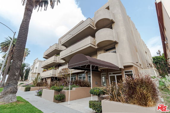 Front view of a multi-story building with a brown awning over the entrance.