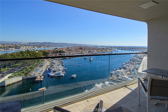 Wide angle view of marina with boats and surrounding cityscape from a building balcony.