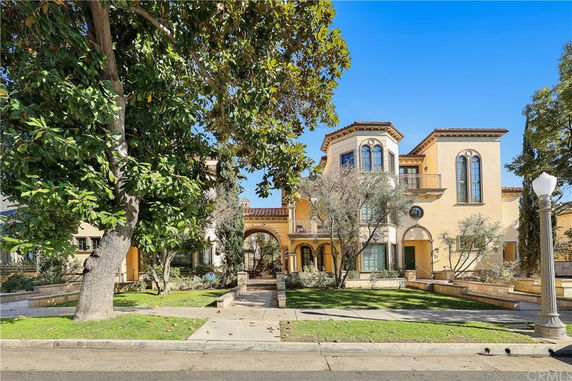 Front view of a large multi-story house with arched windows and a symmetrical design.