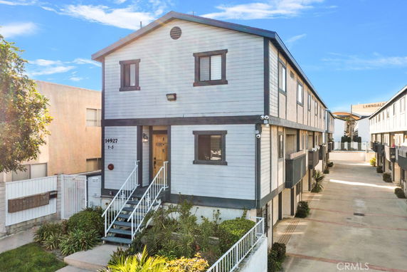 Front view of a multi-story residential building with external stairs and multiple windows.