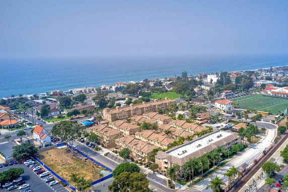 Aerial view of a coastal residential area with multiple houses and buildings near the ocean.
