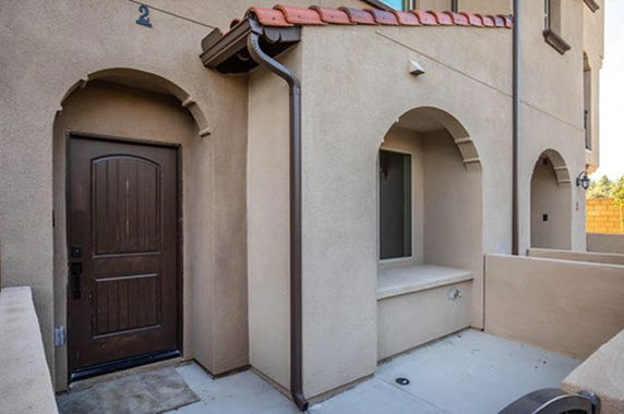Front view of a house entrance with an arched doorway and window.
