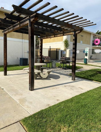 Outdoor view of a pergola structure with picnic tables and barbeque grills.