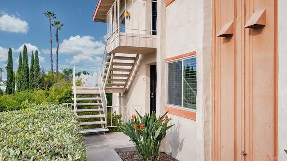 Side view of a two-story building with exterior stairs and windows.