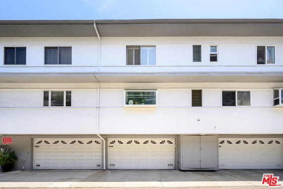 Front view of a multi-story building with several garage doors on the ground level.