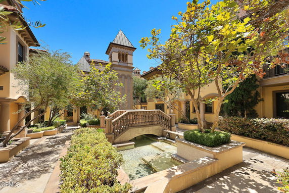 Outdoor courtyard with a bridge, water feature, and surrounding buildings.