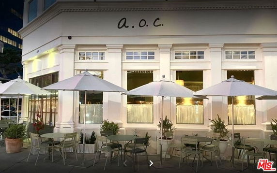 Front view of a building with large windows and outdoor seating.