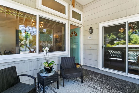 Front view of a house with a partially open door, windows, and patio furniture.