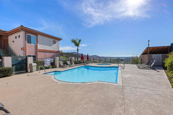 Outdoor swimming pool with lounge chairs and a view of surrounding hills.