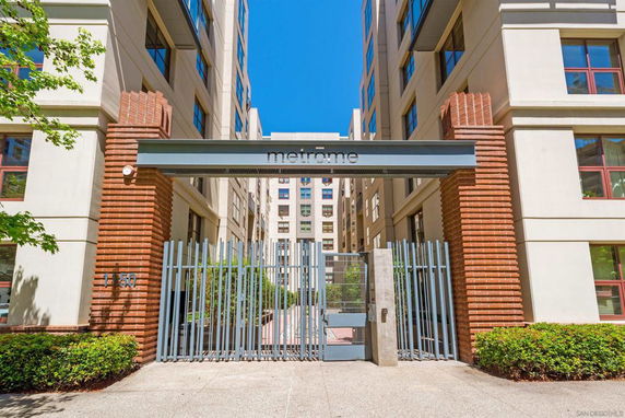 Front view of a modern apartment building entrance with metal gate and brick accents.