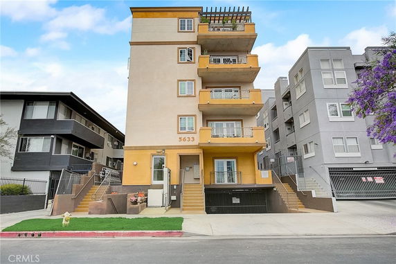 Front view of a multi-story apartment building with balconies and stairs.