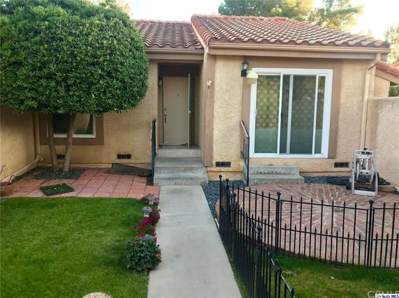 Front view of a house with tiled roof and small front steps leading to a door.