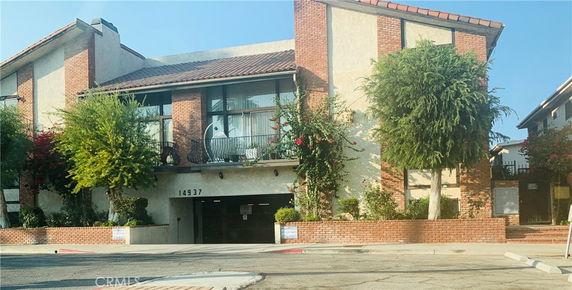 Front view of a multi-story building with brick and stucco exterior and a garage entrance.