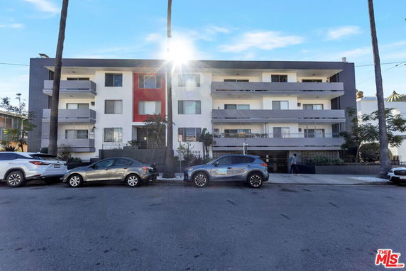 Front view of a multi-story residential building with balconies and a central entrance.
