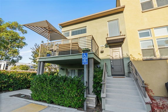 Front view of a multi-story building with an entrance staircase and terrace.