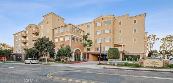 Front view of a multi-story apartment building with a beige exterior and multiple balconies.