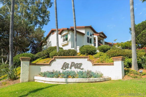 Front view of a multi-story house with a landscaped garden and 'La Paz' sign.