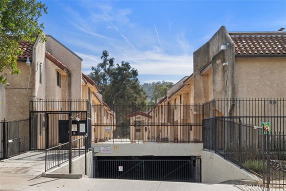Front view of a residential complex with a gated entrance and parking.
