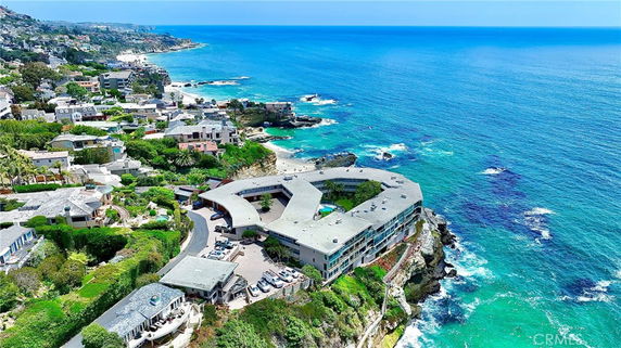 Aerial view of a coastal building complex with ocean and surrounding houses.