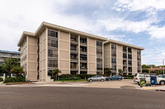Front view of a multi-story apartment building with parking area.