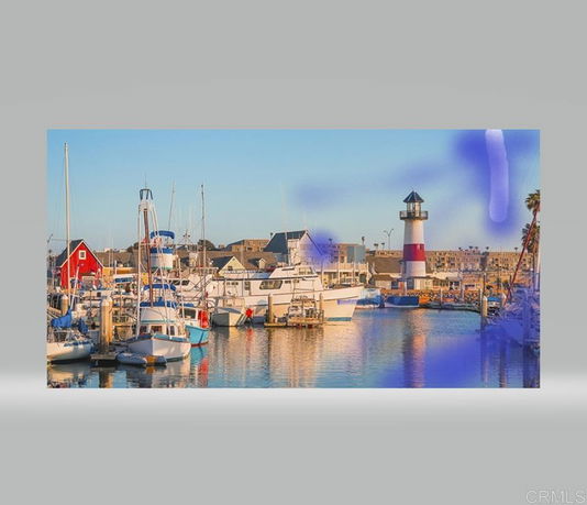 View of a marina with boats and a lighthouse in the background.
