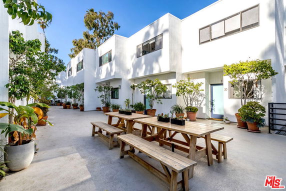 Front view of a modern apartment building with white exterior and outdoor seating area.